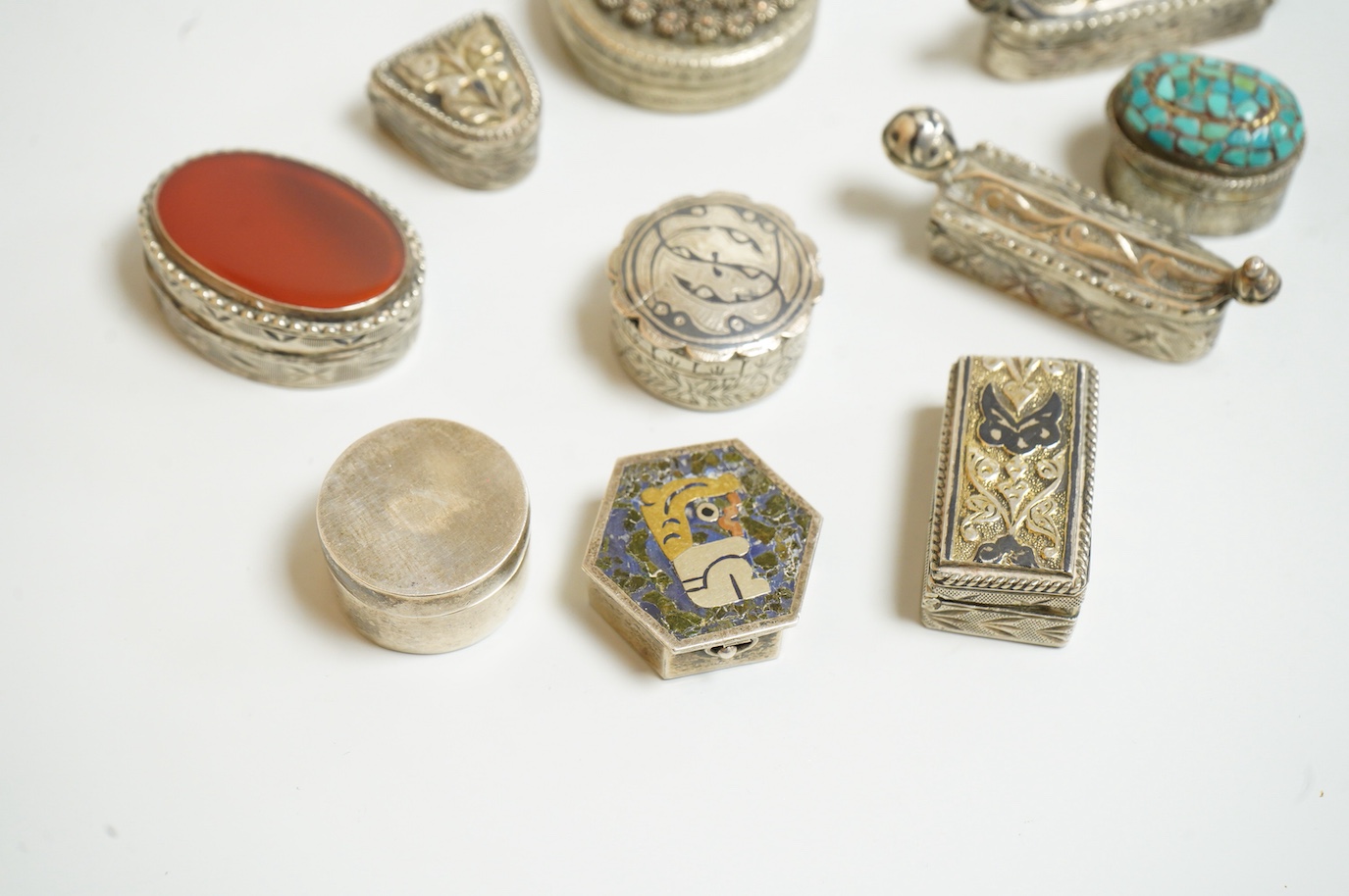 A collection of assorted pill boxes including one modern circular silver, a Mexican 925, six continental white metal, one inset with chalcedony and two with niello decoration and three other unmarked white metal pill box